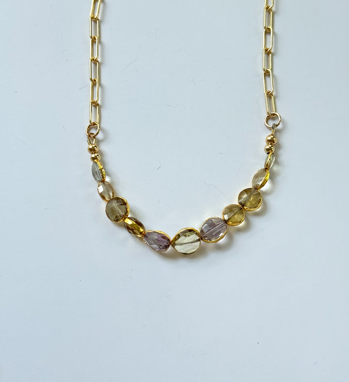 Necklace with multicolored gemstone beads on a gold chain against a white background